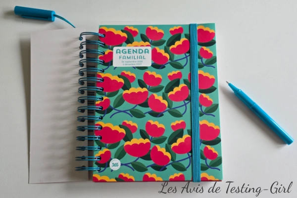 Agenda familial Mémoniak fermé avec stylo bleu, posé sur une table claire